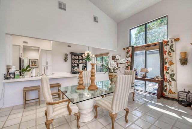 dining space featuring a chandelier, light tile flooring, and high vaulted ceiling