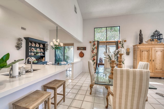 dining area with a notable chandelier, a textured ceiling, high vaulted ceiling, and light tile flooring