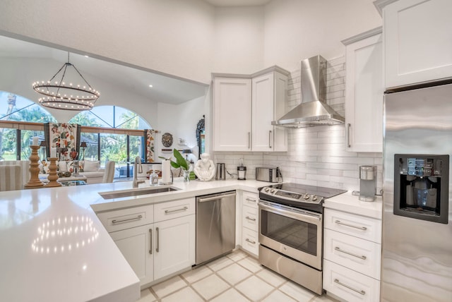 kitchen featuring sink, stainless steel appliances, wall chimney range hood, tasteful backsplash, and decorative light fixtures