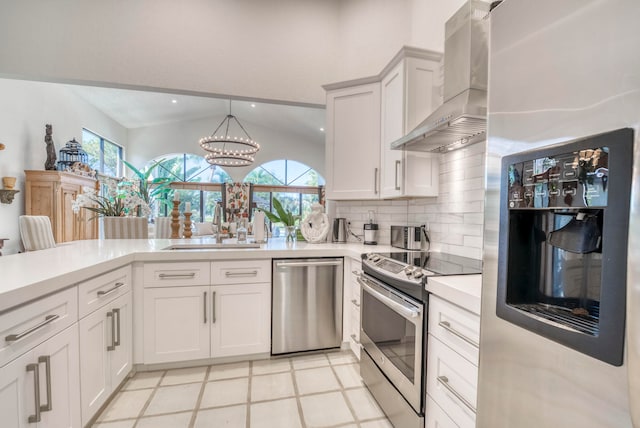 kitchen featuring pendant lighting, light tile floors, wall chimney range hood, white cabinetry, and appliances with stainless steel finishes