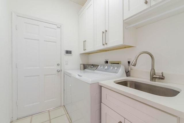 laundry area featuring light tile flooring, separate washer and dryer, cabinets, and sink