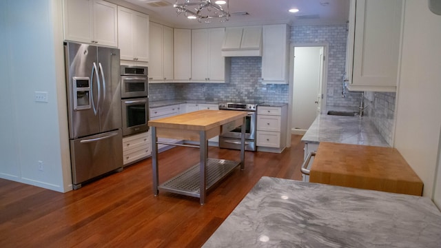 kitchen with an inviting chandelier, white cabinets, appliances with stainless steel finishes, and dark wood-type flooring