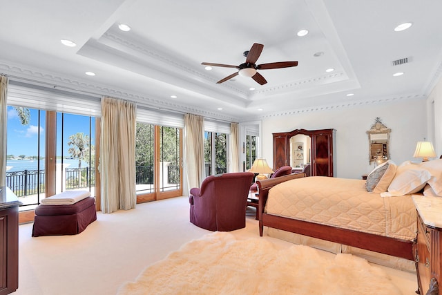 bedroom with a water view, light carpet, a raised ceiling, access to outside, and ornamental molding