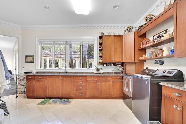 kitchen featuring stone counters, crown molding, washing machine and clothes dryer, sink, and light tile floors