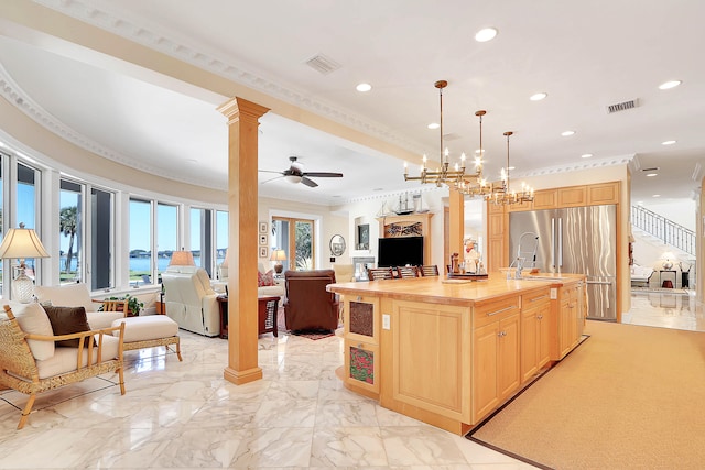 kitchen with a kitchen island with sink, decorative light fixtures, ceiling fan with notable chandelier, crown molding, and ornate columns