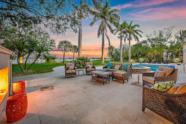 patio terrace at dusk with a lawn and an outdoor living space with a fire pit