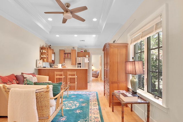 living room with crown molding, light hardwood / wood-style floors, ceiling fan, and a raised ceiling