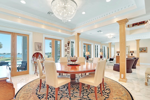 tiled dining area with french doors, crown molding, ornate columns, a raised ceiling, and a chandelier