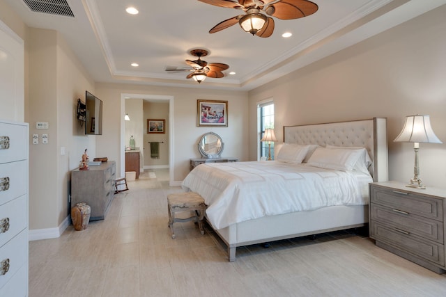 bedroom featuring ensuite bathroom, ornamental molding, ceiling fan, and a tray ceiling