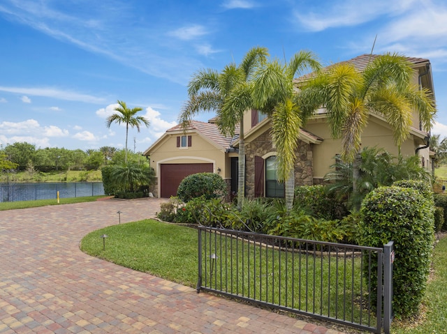 view of front facade featuring a front yard, a water view, and a garage