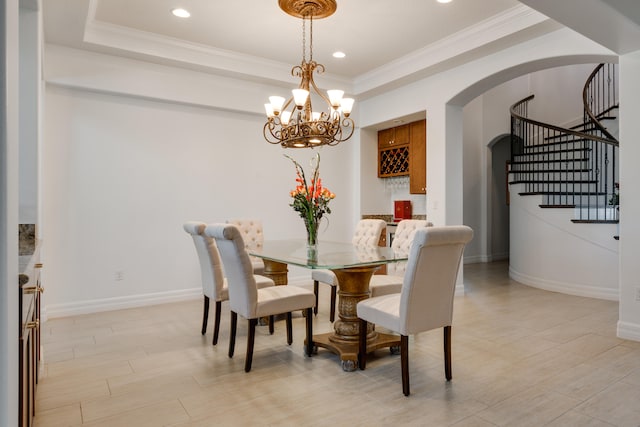 dining room with a chandelier, a raised ceiling, and crown molding