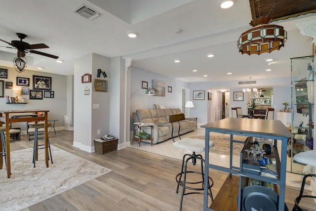 interior space with a textured ceiling, ceiling fan with notable chandelier, and light wood-type flooring