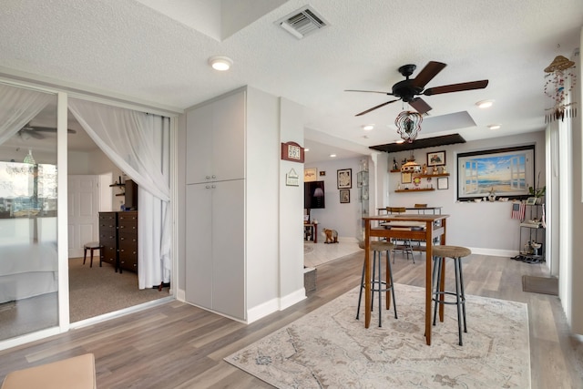 dining area with a textured ceiling, light colored carpet, and ceiling fan