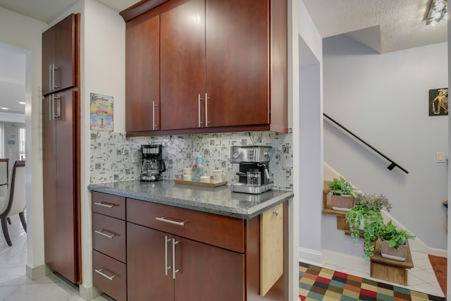 kitchen with tasteful backsplash, dark stone countertops, light tile floors, and a textured ceiling