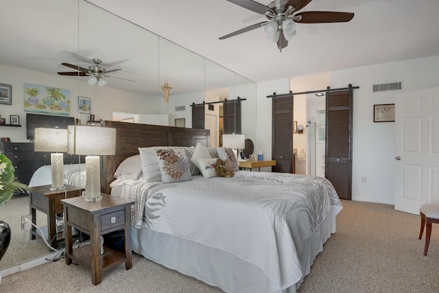 carpeted bedroom with a barn door and ceiling fan