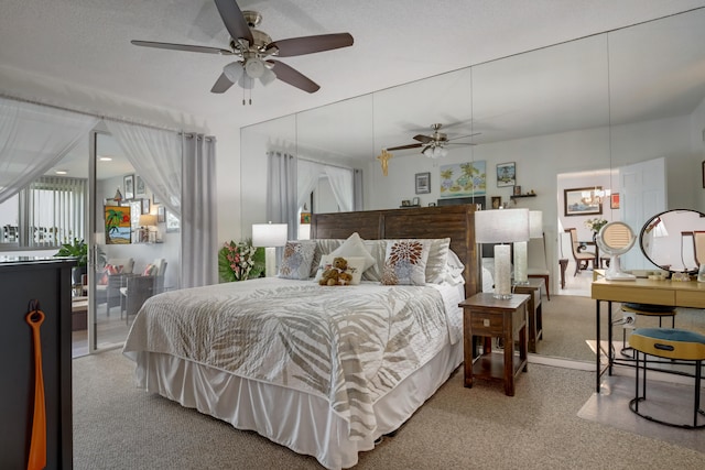 carpeted bedroom featuring ceiling fan with notable chandelier