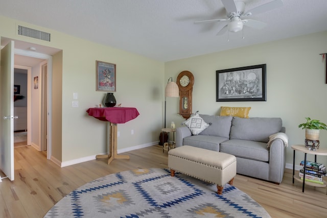 living room with light hardwood / wood-style flooring, ceiling fan, and a textured ceiling