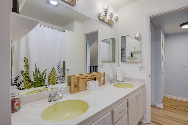 bathroom featuring vanity with extensive cabinet space, dual sinks, and hardwood / wood-style floors