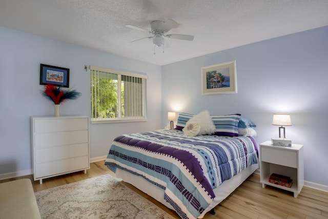 bedroom with a textured ceiling, ceiling fan, and light wood-type flooring