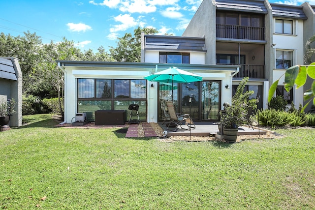 rear view of house with a balcony, a lawn, and a patio area