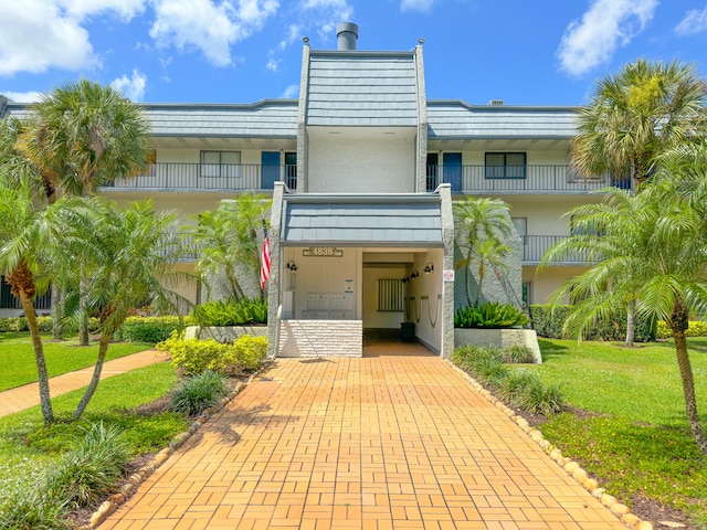 view of front facade with a balcony and a front lawn