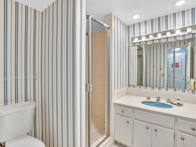 bathroom featuring toilet, a shower with door, and vanity