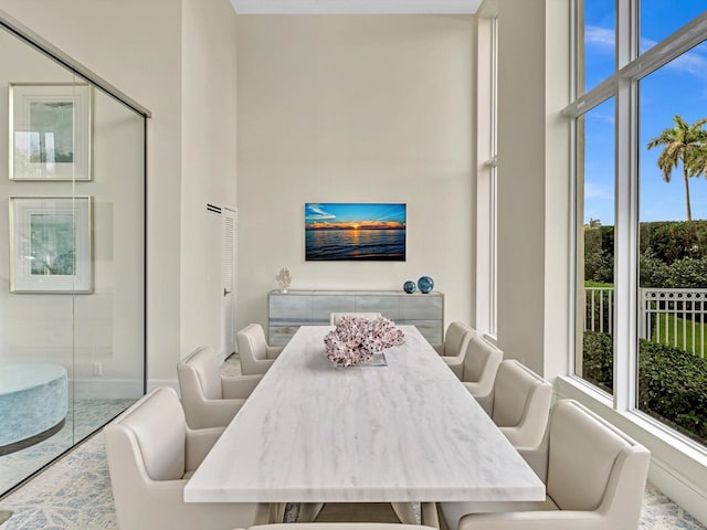 tiled dining room featuring a healthy amount of sunlight and a towering ceiling