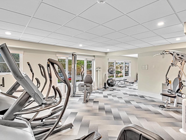 gym with light carpet and a paneled ceiling