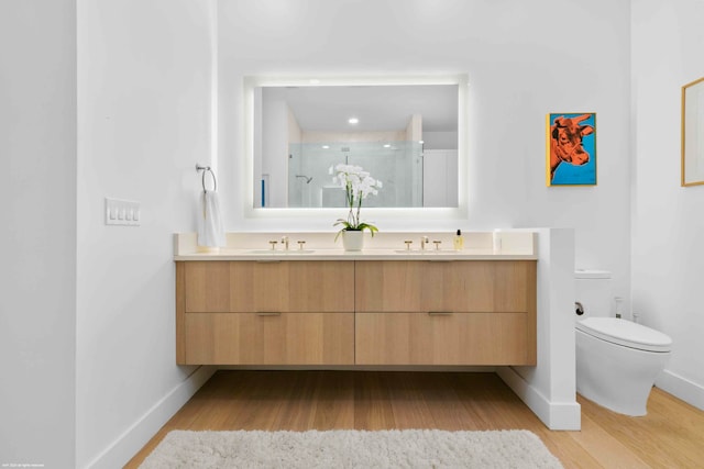 bathroom featuring dual vanity, toilet, and hardwood / wood-style flooring