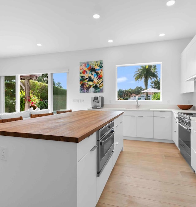 kitchen featuring light hardwood / wood-style flooring, stainless steel appliances, a wealth of natural light, and butcher block countertops