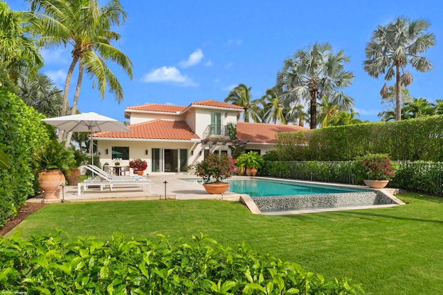 rear view of property featuring a yard, a fenced in pool, and a patio area