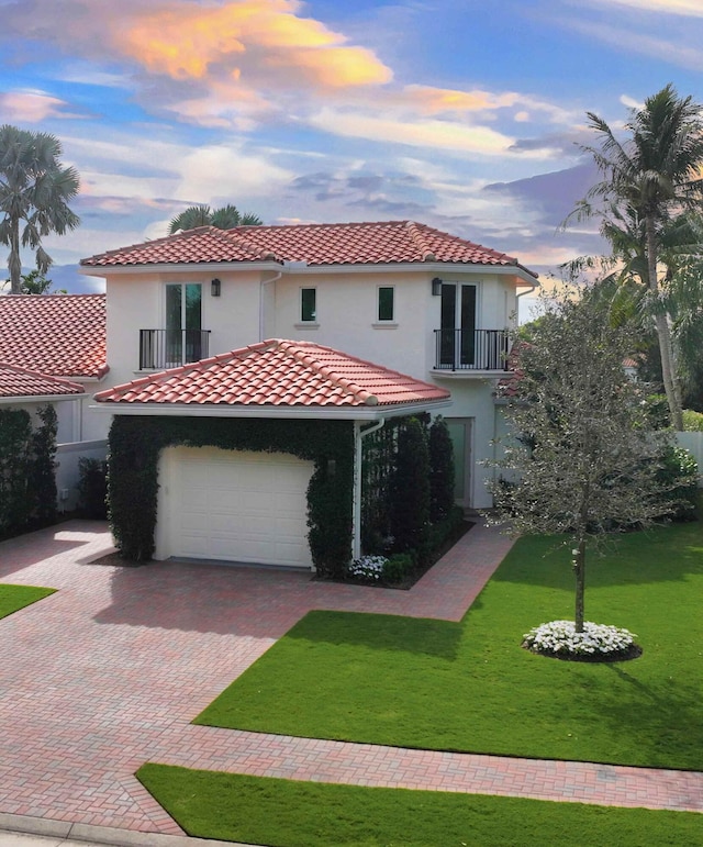 mediterranean / spanish home featuring a lawn, a balcony, and a garage