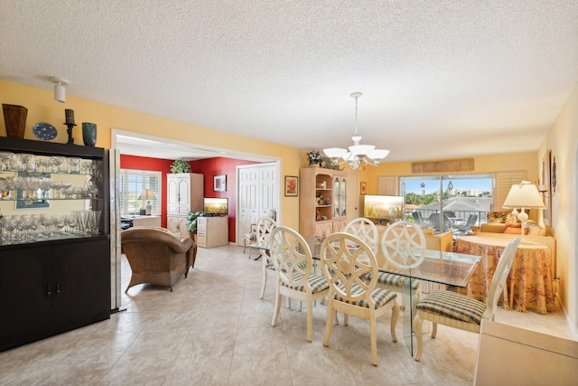 dining space with an inviting chandelier, light tile patterned flooring, and a textured ceiling