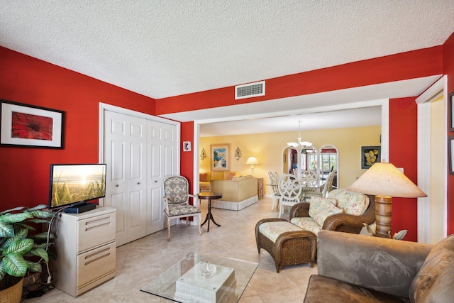 living room featuring a chandelier, a textured ceiling, and light tile patterned floors