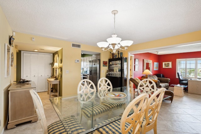 tiled dining space with a textured ceiling and a notable chandelier