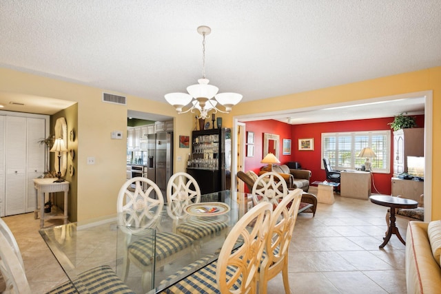 tiled dining space featuring a notable chandelier and a textured ceiling