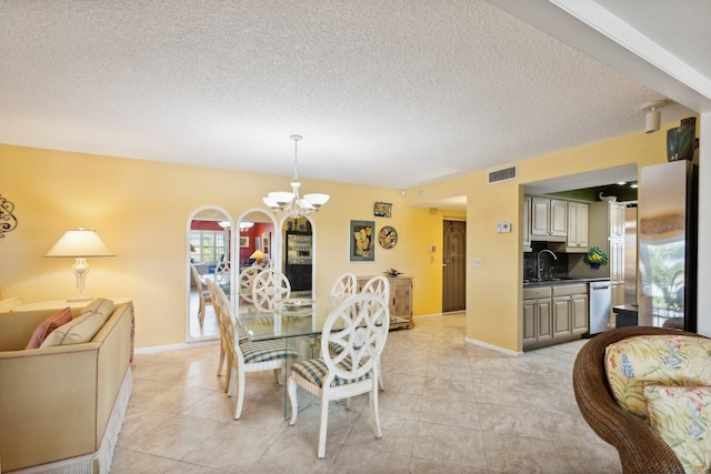 dining room with an inviting chandelier, sink, light tile patterned floors, and a textured ceiling