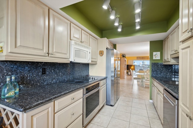 kitchen with dark stone countertops, stainless steel appliances, decorative backsplash, and light tile patterned floors