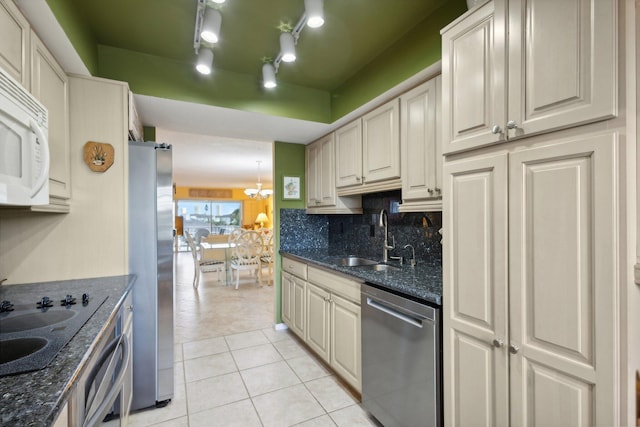 kitchen with sink, appliances with stainless steel finishes, tasteful backsplash, light tile patterned flooring, and dark stone counters