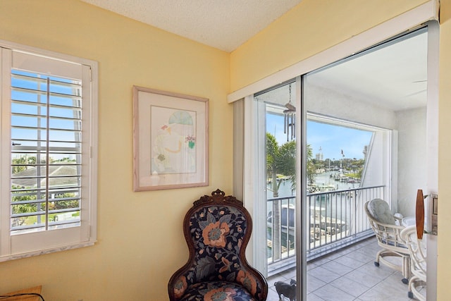 sitting room with tile patterned flooring, a water view, and a textured ceiling