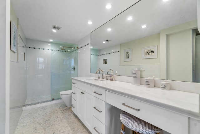 bathroom featuring a shower with door, large vanity, and toilet