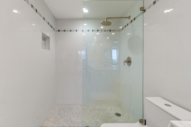 bathroom featuring a tile shower and toilet