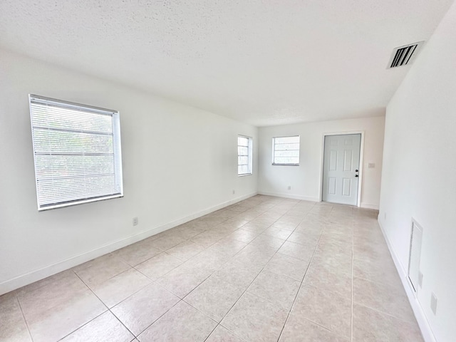 tiled spare room with a textured ceiling