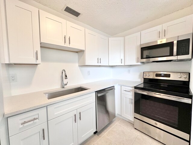 kitchen featuring light stone counters, a textured ceiling, white cabinets, sink, and stainless steel appliances