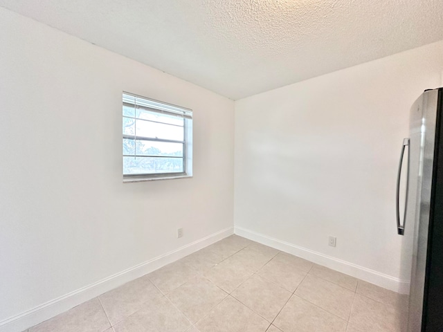 empty room with light tile flooring and a textured ceiling