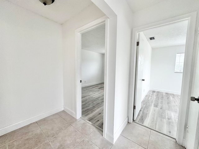 hall with light tile floors and a textured ceiling