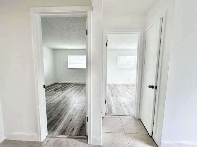 hall with a textured ceiling and light tile flooring