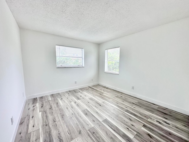 empty room with light hardwood / wood-style flooring and a textured ceiling