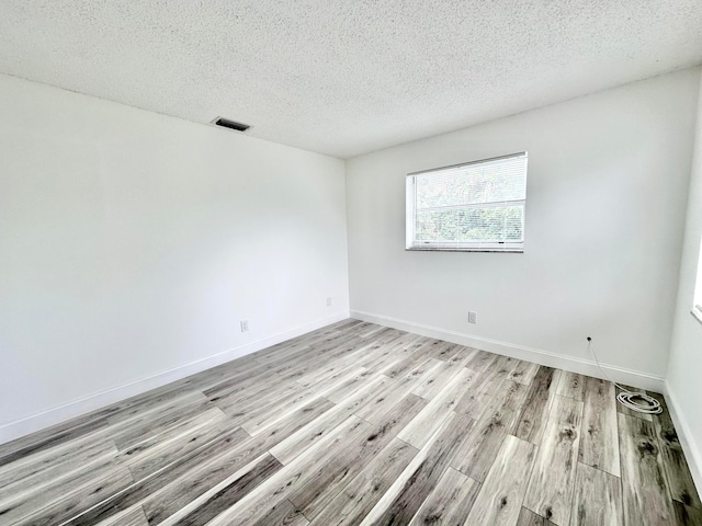 unfurnished room featuring light hardwood / wood-style flooring and a textured ceiling