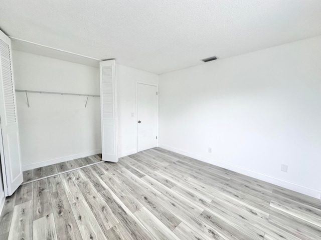 unfurnished bedroom with light hardwood / wood-style flooring, a closet, and a textured ceiling